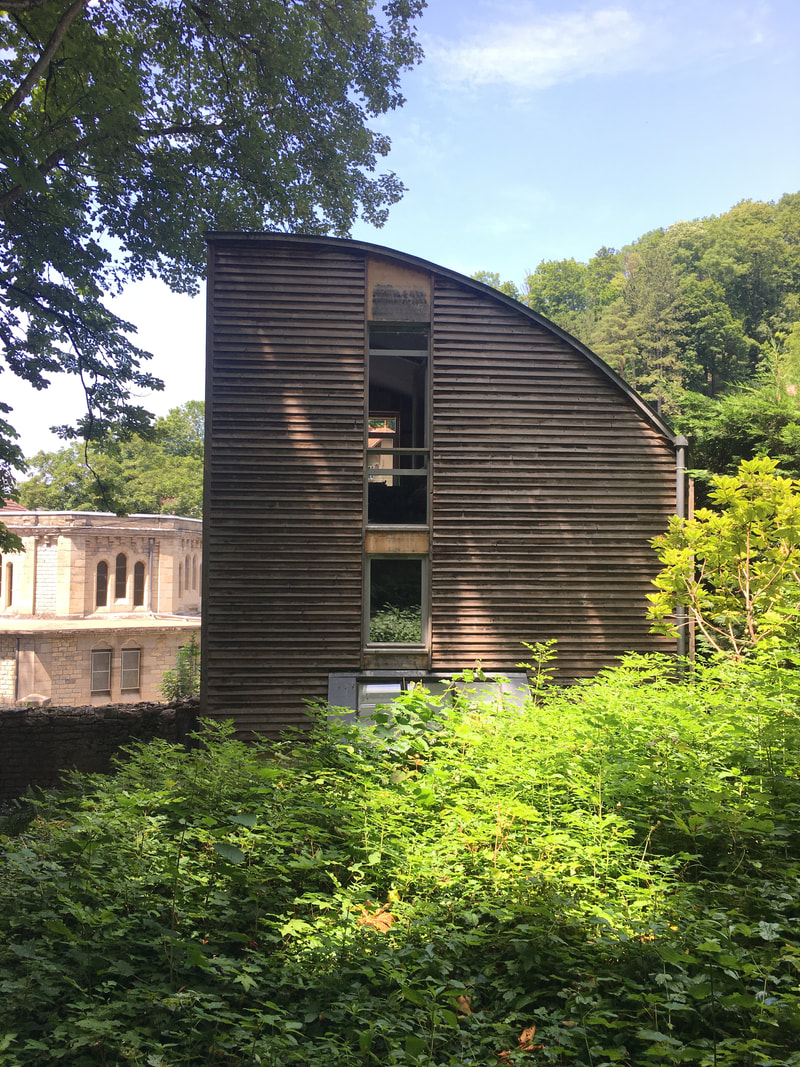 Façade en bois à toiture courbe de l'agence Atelier Haton, dans la verdure du quartier de Bregille à Besançon