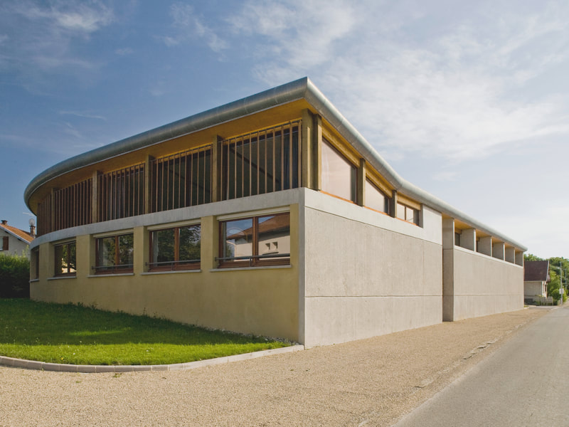 École maternelle de Grandfontaine : volume courbe en béton et bois implanté en limite de rue, brise-soleil en bois