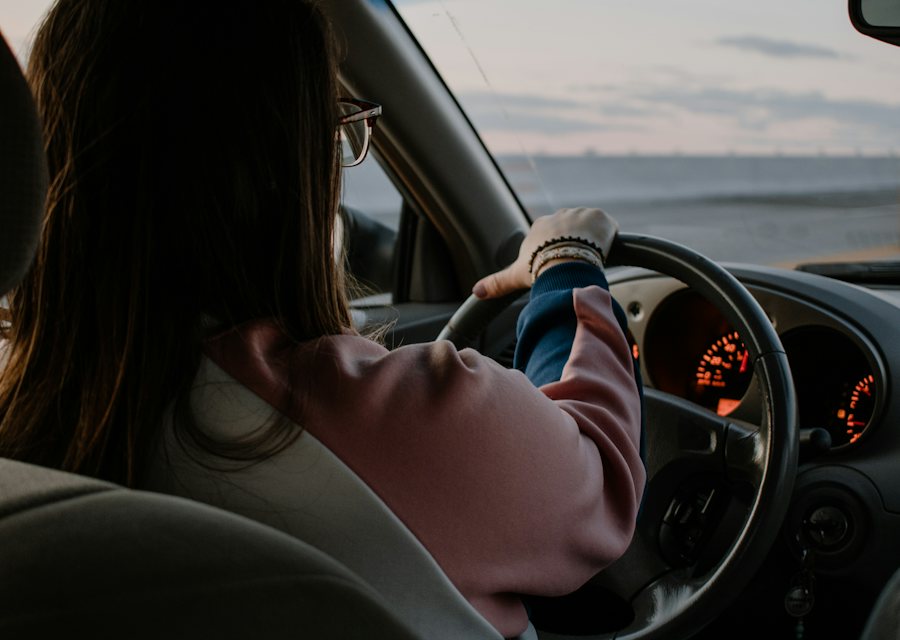 Jeune conductrice au volant de sa voiture, mains sur le volant, sur une route dégagée