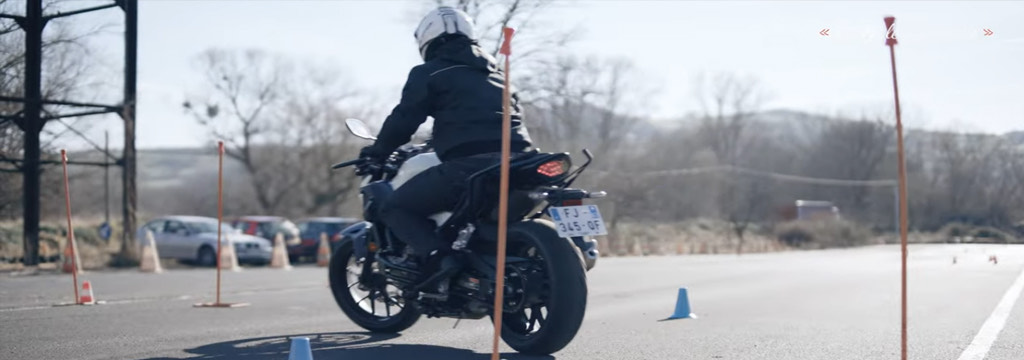 Élève motard en slalom entre les piquets sur la piste privée de la moto-école