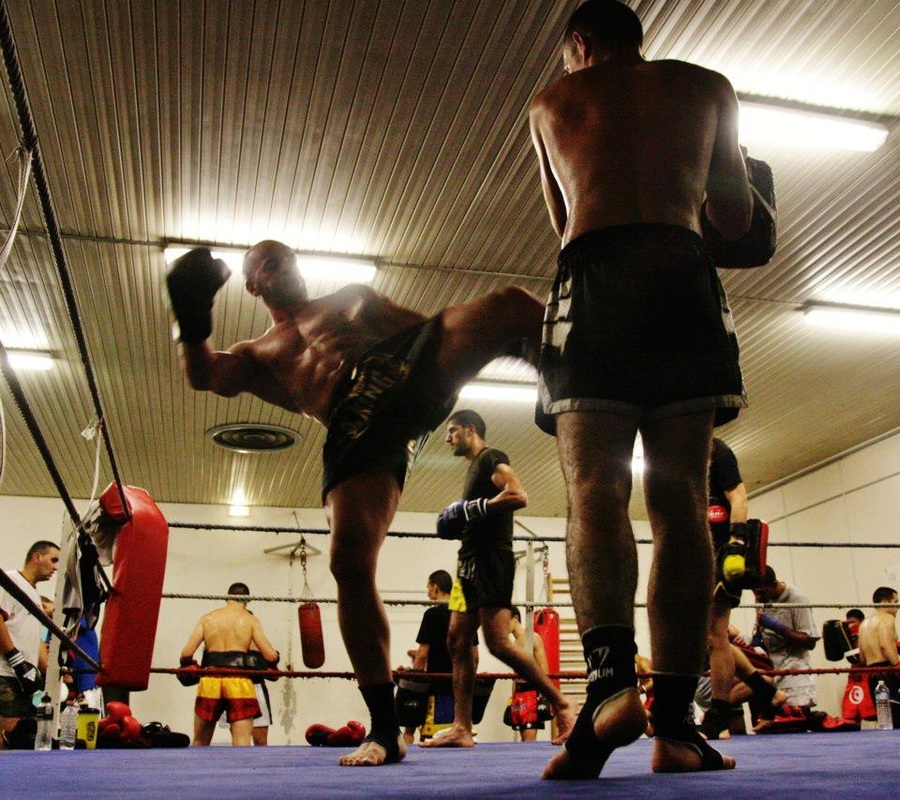 Boxeur exécutant un coup de pied haut sur le ring pendant un entraînement de Muay Thaï au club Grenoble Muaythai