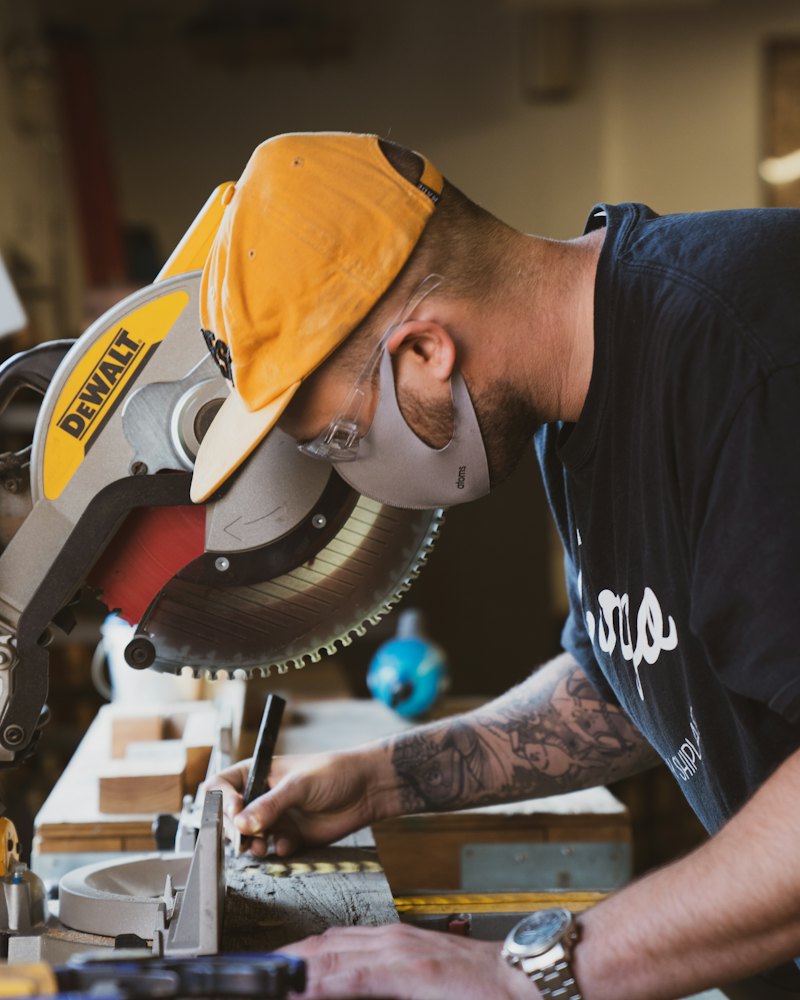 Artisan menuisier en atelier réglant une scie circulaire avant la coupe