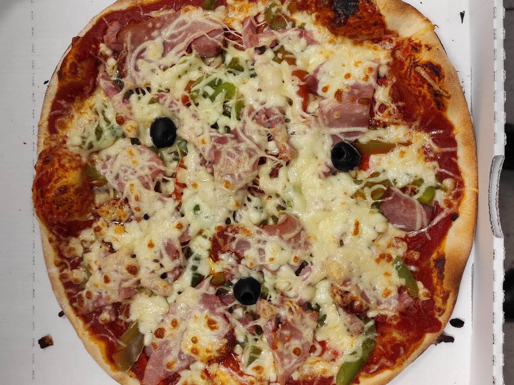 Pizza maison jambon, champignons, poivrons et olives dans sa boîte à emporter