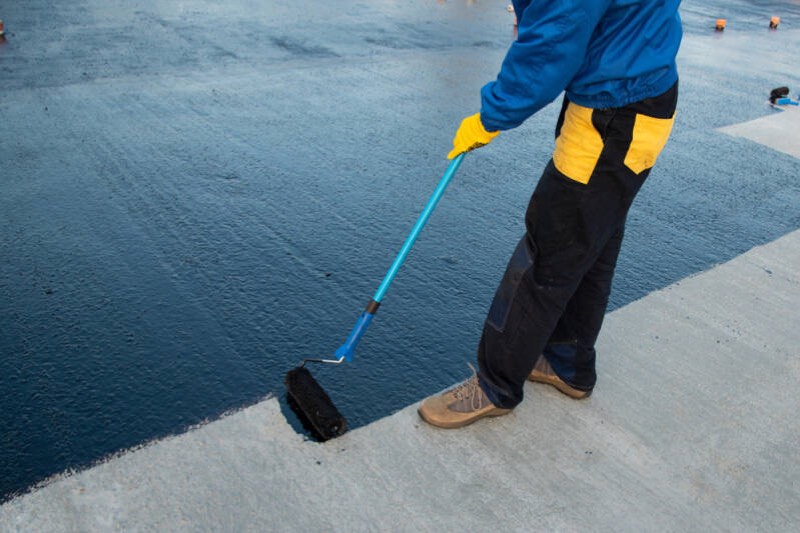 Application d’une résine d’étanchéité bleue sur une toiture-terrasse