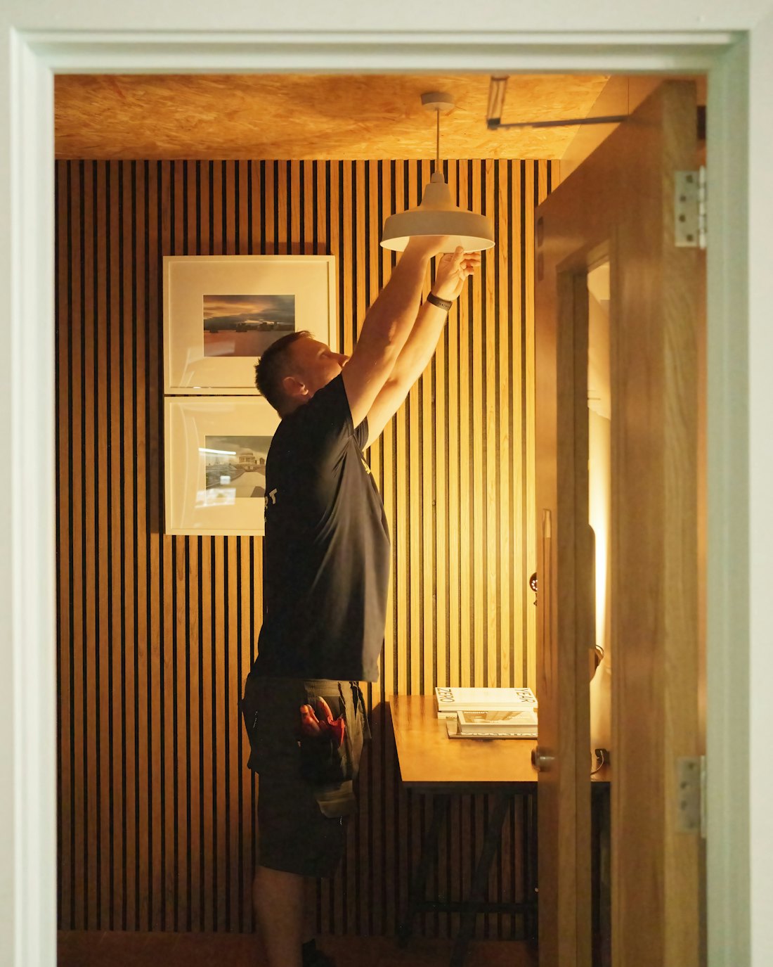 Artisan d'EVDN Multi-Services installant un luminaire dans une pièce en cours d'aménagement.
