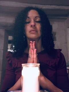 Farah, magnétiseuse énergéticienne, les mains jointes devant une bougie allumée