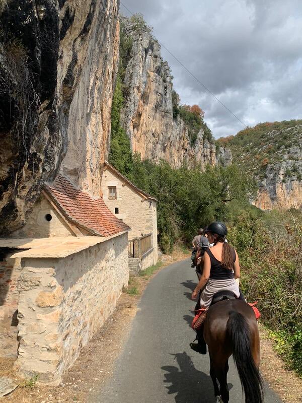 Cavaliers faisant halte devant une chapelle troglodytique au pied d'une falaise