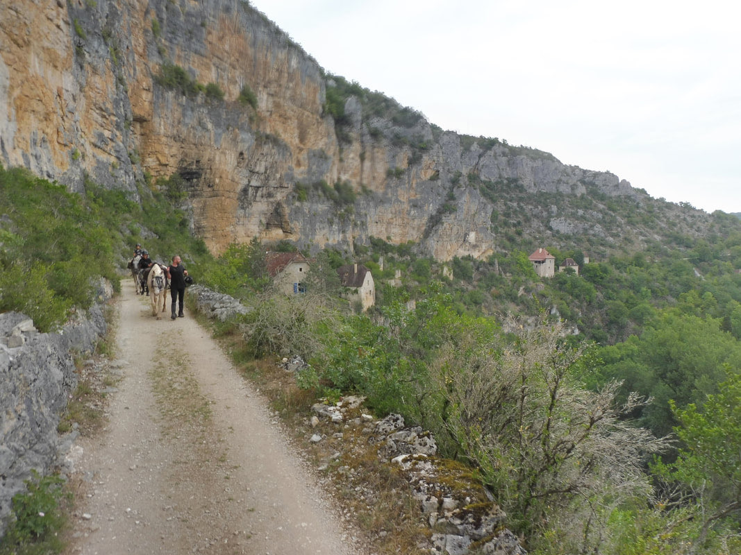 Cavaliers progressant sur un sentier face aux falaises du causse
