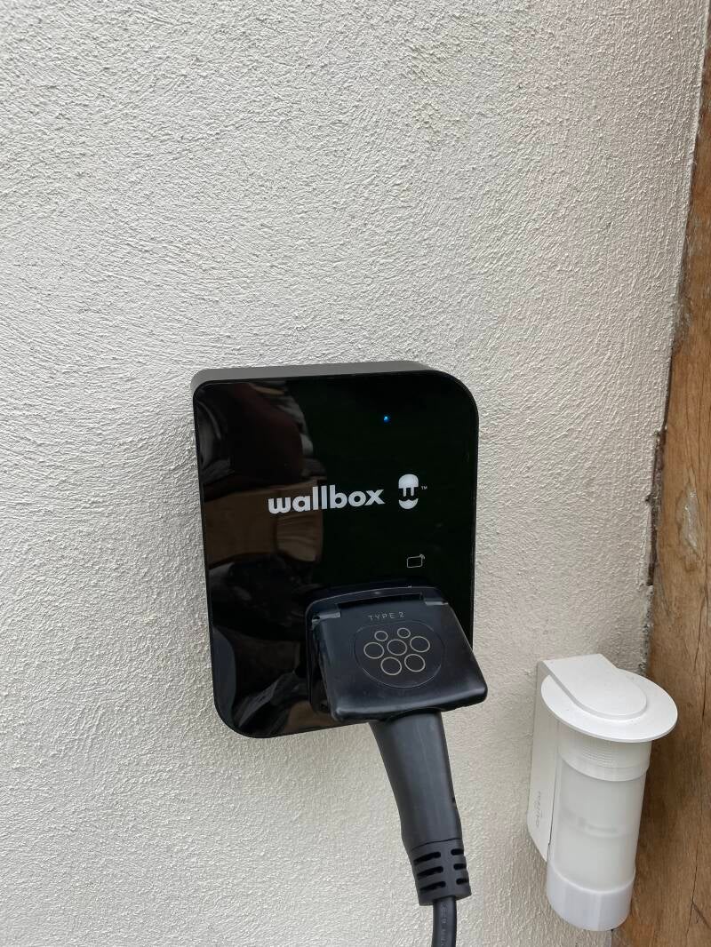 Borne de recharge murale Wallbox pour véhicule électrique installée sur une façade