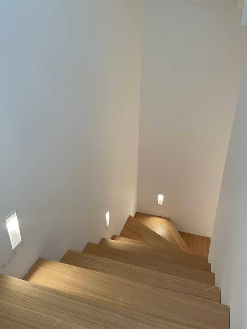 Escalier en bois éclairé par des spots LED encastrés dans le mur