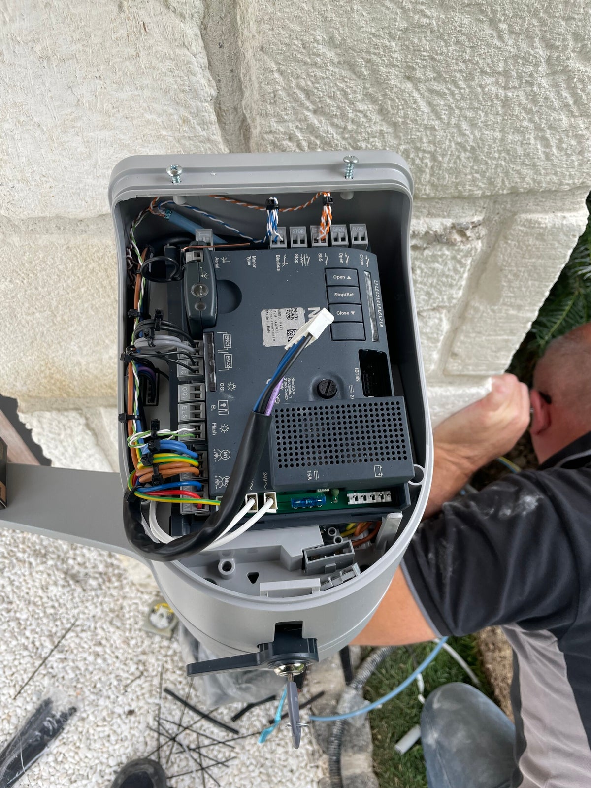 Technicien Bailly Électricité raccordant la carte électronique d'une motorisation de portail