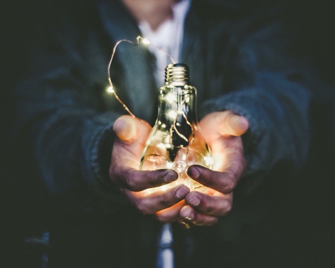 Mains tenant délicatement une ampoule allumée, symbole de prise de conscience