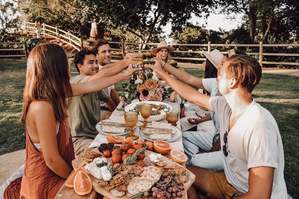 Repas convivial en plein air autour d'une grande table garnie de fruits et légumes frais