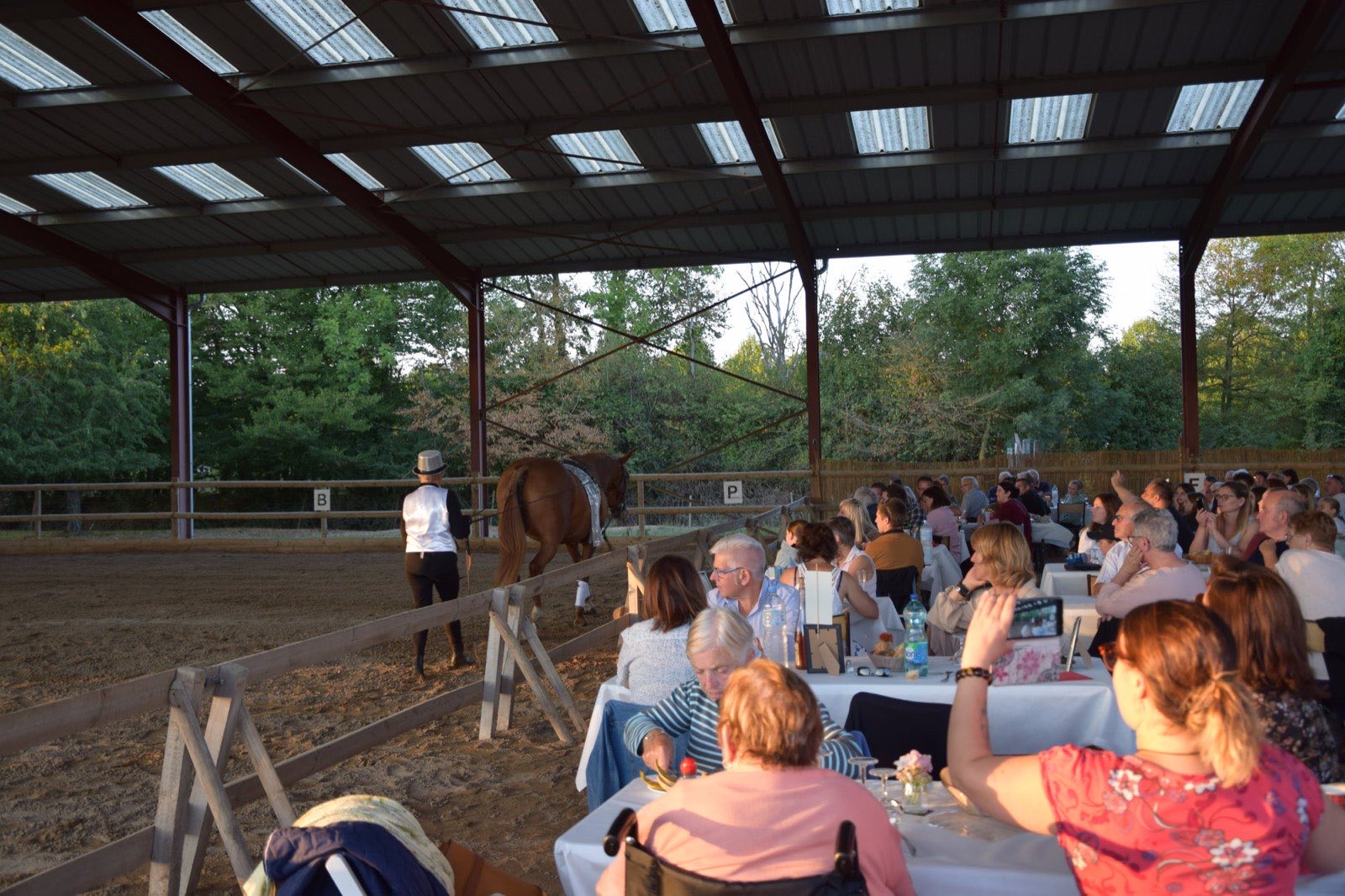 Le public attablé sous le manège couvert pendant un cabaret équestre des Écuries Évasions