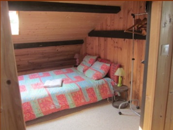 Chambre d'hôtes du gîte avec lit double et murs en bois