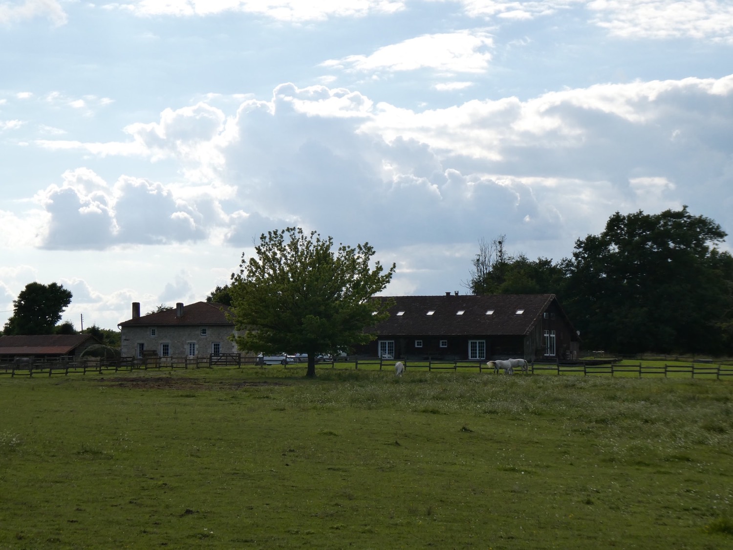 La grange de Majouraou vue depuis la prairie, sous un ciel nuageux