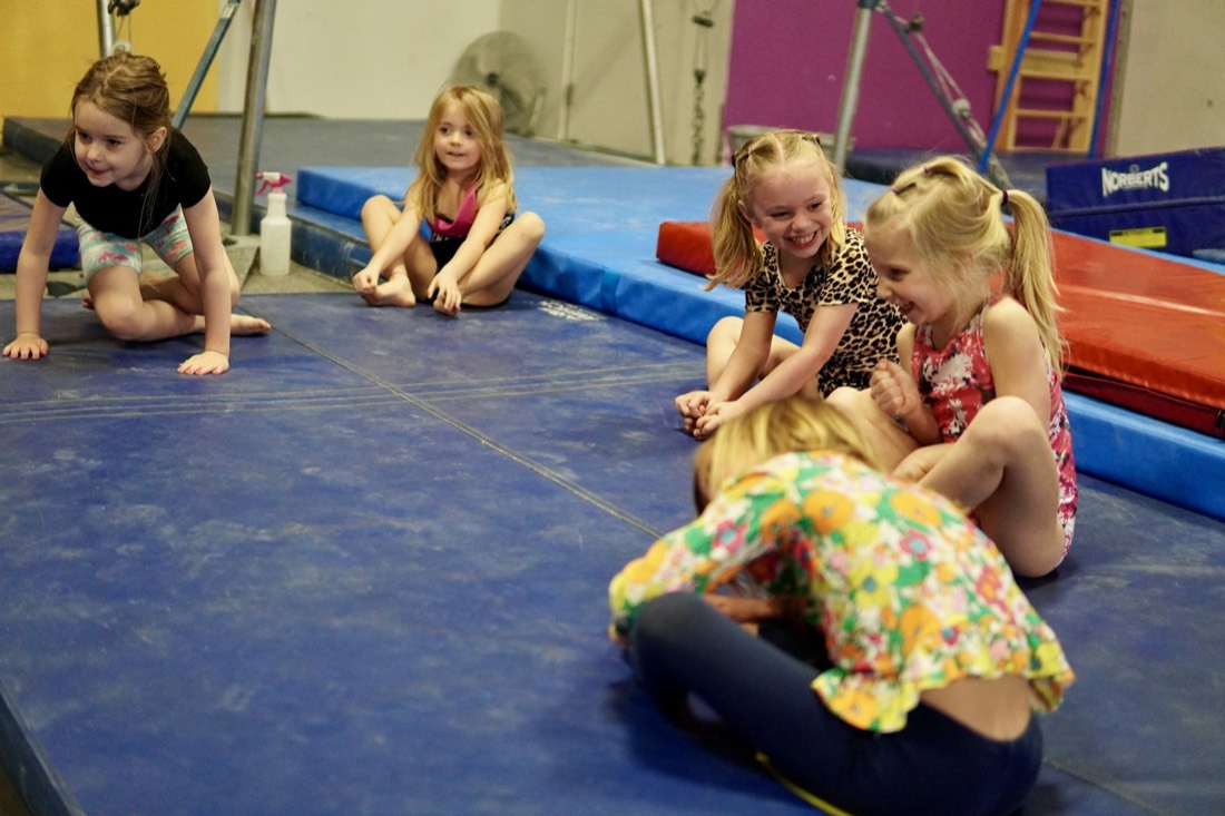 Jeunes enfants assis sur les tapis pendant un cours d'éveil gymnique