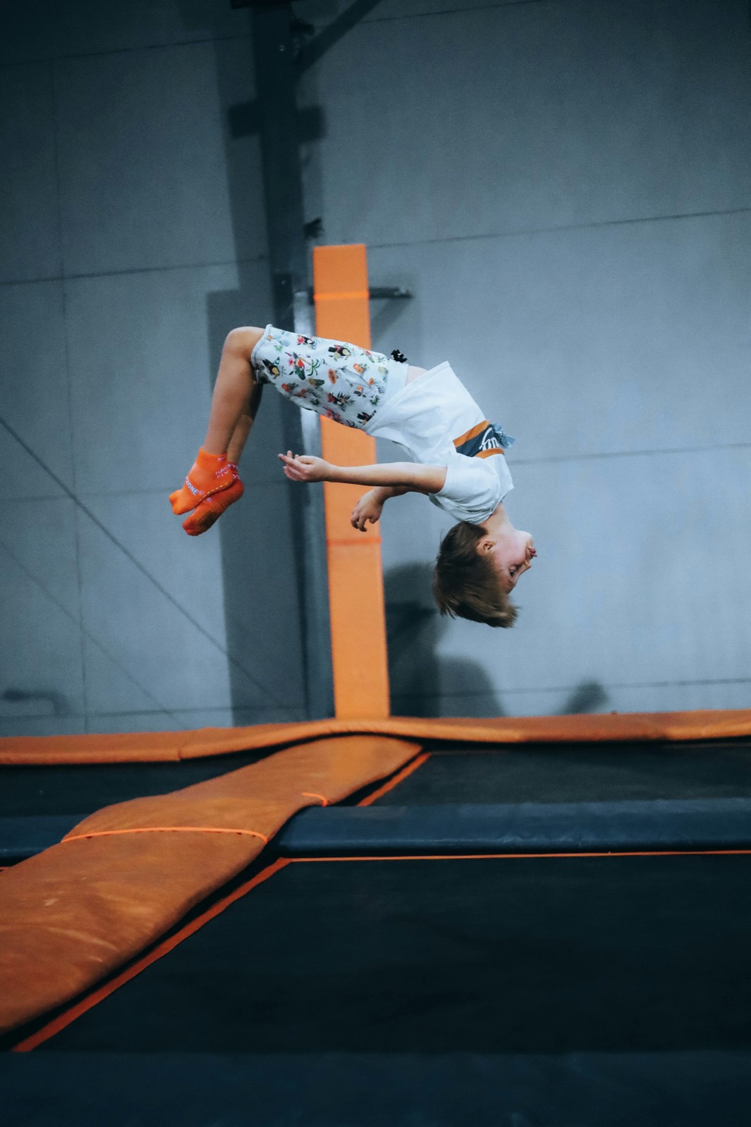 Jeune gymnaste réalisant un salto arrière sur un trampoline dans un gymnase