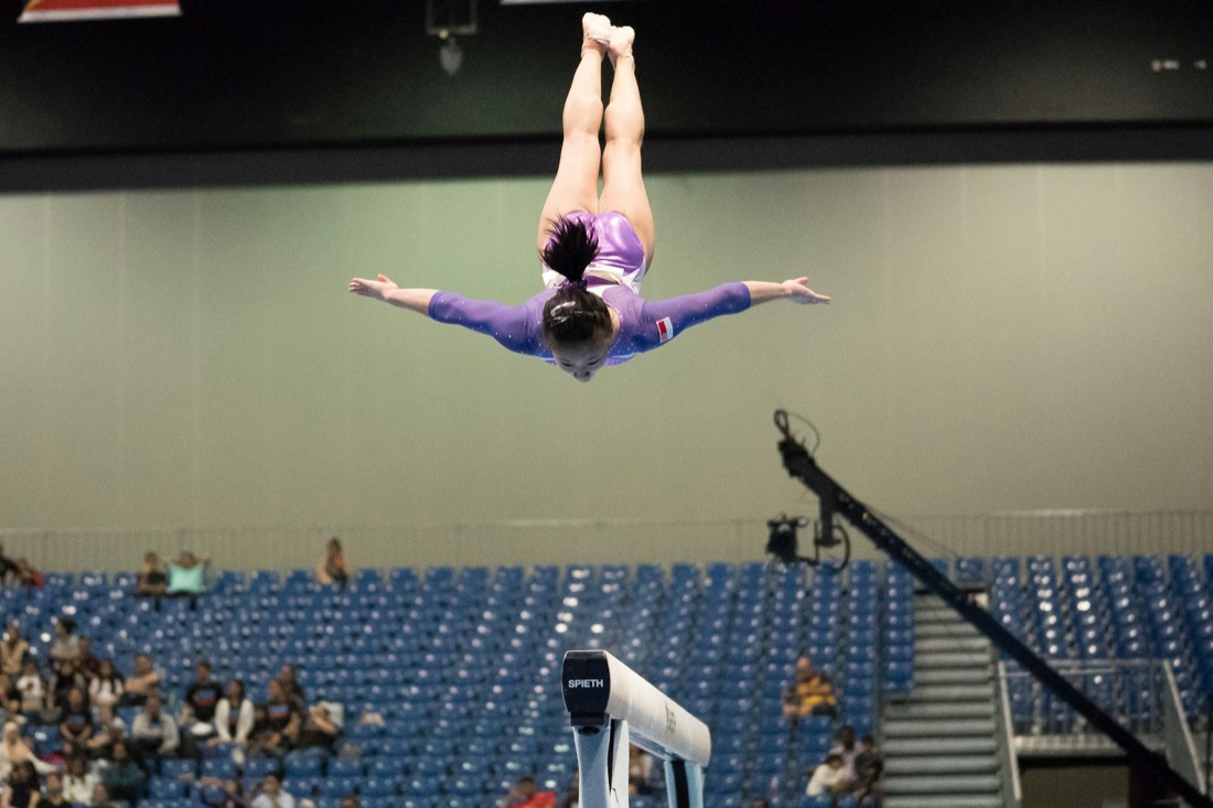 Gymnaste en plein saut acrobatique lors d'une compétition en salle